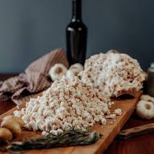 Rendered beef tallow on a wooden cutting board, with a bottle and garlic in the background.